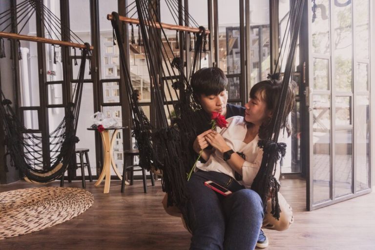 couple-sitting-black-cloth-hammock_23-2147592901