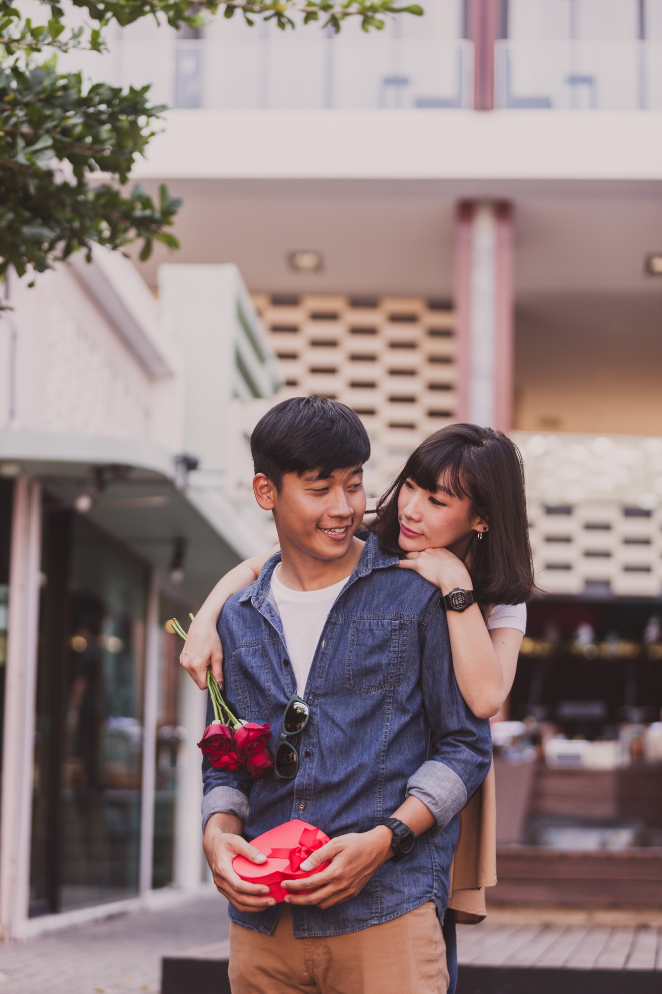 girl-hugging-man-from-this-holds-roses-gift